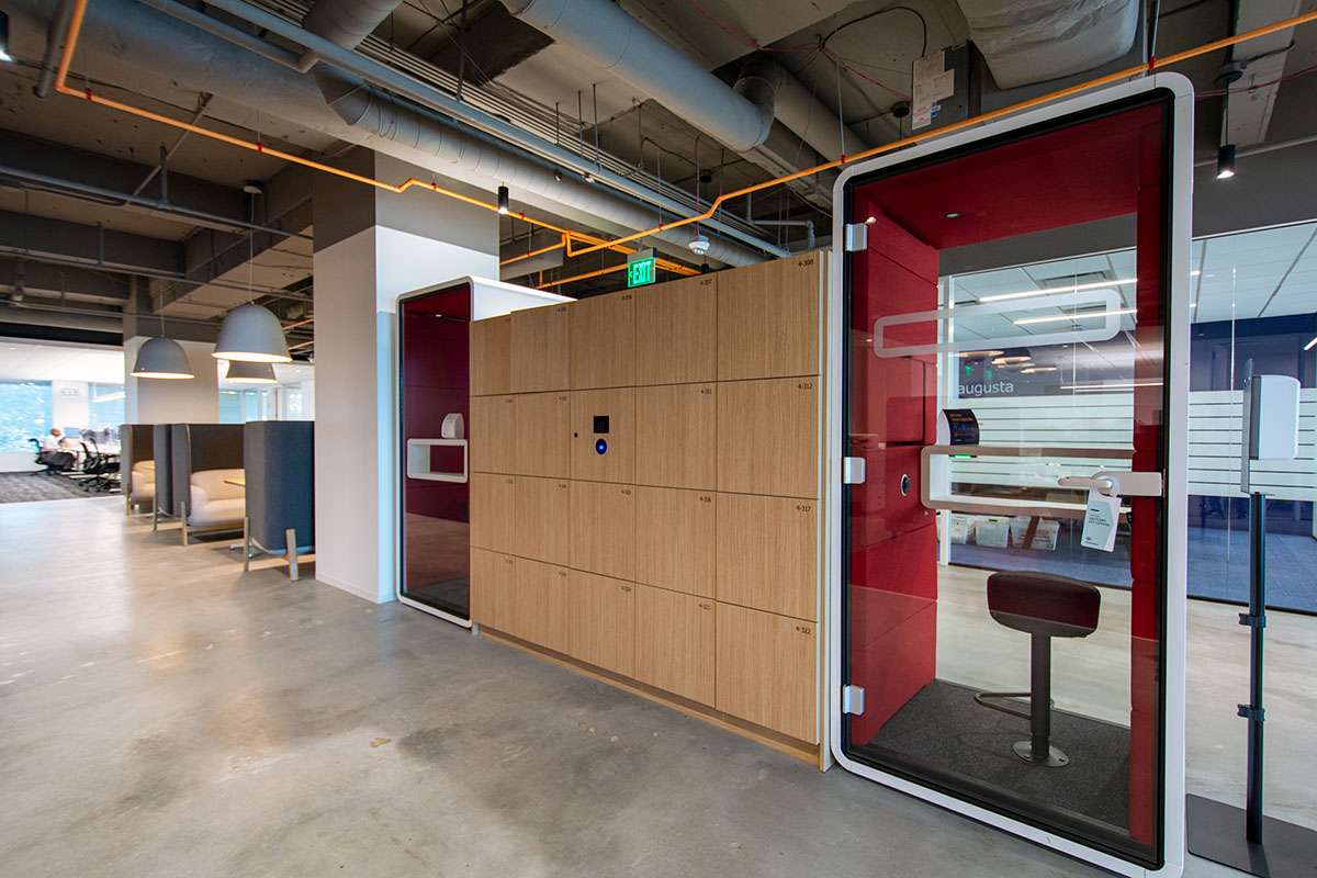 A dedicated phone booth and integrated smart lockers in a modern, agile office environment.